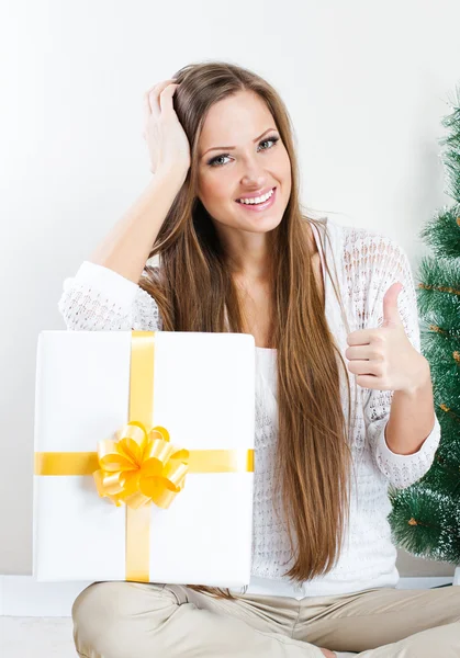 Woman with christmas gift thumbs up — Stock Photo, Image