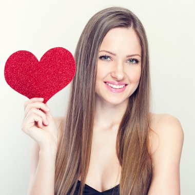 Kırmızı kalp tutan genç mutlu kadın.