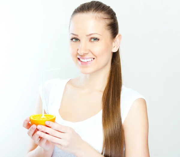 Atraktivní usměvavá mladá žena pít pomerančový džus přímo z ovoce — Stock fotografie