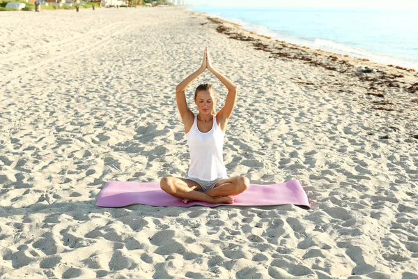 Mujer haciendo yoga en la playa al amanecer — Foto de Stock