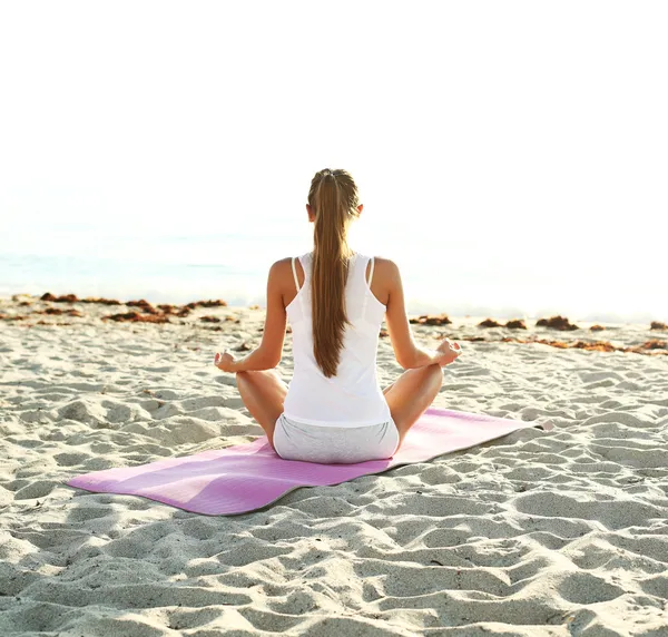 Güneş doğarken kumsalda yoga yaparken kadın — Stok fotoğraf