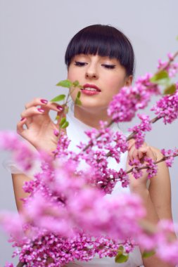 pembe çiçekler arasında gülümseyen güzel kadın