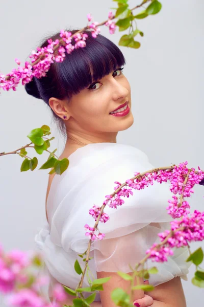 Mooie lachende vrouw onder roze bloemen — Stockfoto