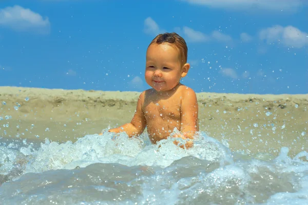 Cute baby boy in water wave splash on the beach — Stock Photo, Image