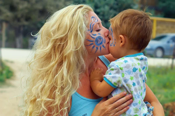 Face-painted mother kissing her little child — Stock Photo, Image