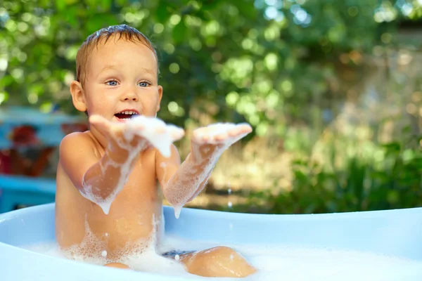 Милий хлопчик розважається в бульбашковій ванні на відкритому повітрі — стокове фото