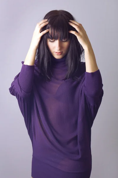 Donna alla moda attraente in abito viola che si tiene per mano sui capelli. isolare — Foto Stock