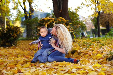 çekici kıvırcık anne ve oğlu düşen yapraklar halı üzerinde oturan bir