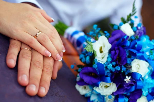 Gros plan des mains des mariés avec anneaux et bouquet — Photo