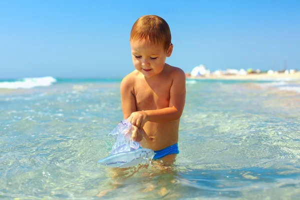 Curious baby boy catches jellyfish in the sea — Stock Photo, Image
