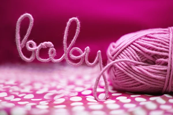 Baby word made of yarn among pink textile — Stock Photo, Image