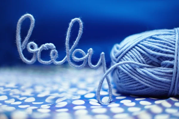 Baby word made of yarn among blue textile — Stock Photo, Image