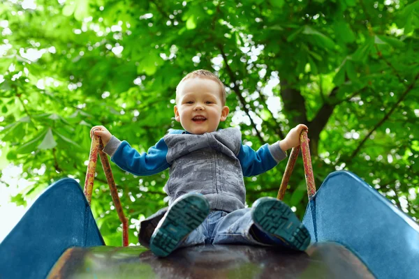 春の公園で子供のスライド上で楽しんで小さな男の子 — ストック写真