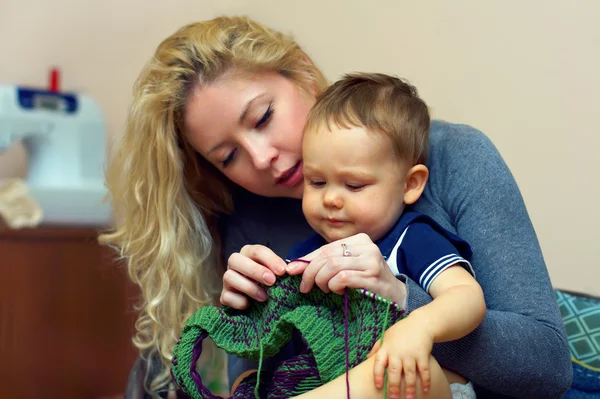 Attractive young mother teach her little baby boy knitting, insi — Stock Photo, Image