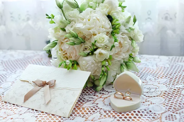 Wedding bouquet, rings and card on lace tablecloth — Stock Photo, Image
