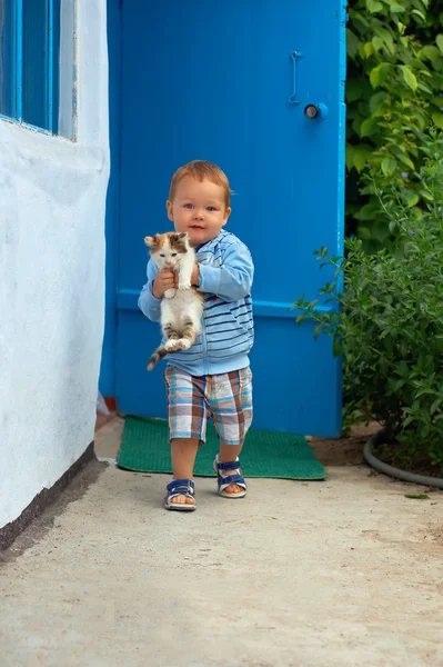Cute baby boy carrying kitten. rural exterior — Stock Photo, Image