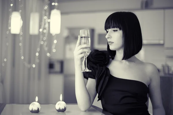 Elegante brunette vrouw met glas van drank zit aan de tafel, celebratin — Stockfoto