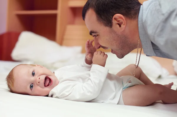 Bebekle oynayan genç mutlu baba. adam ve bebek yalan söylüyorsun — Stok fotoğraf