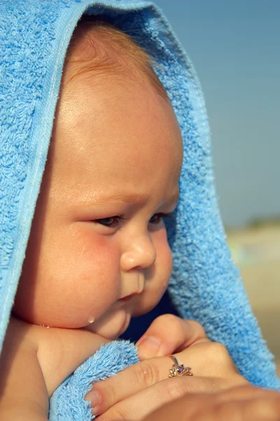 Close-up portrait of small wet baby in blue towel. outdoors — Stock Photo, Image