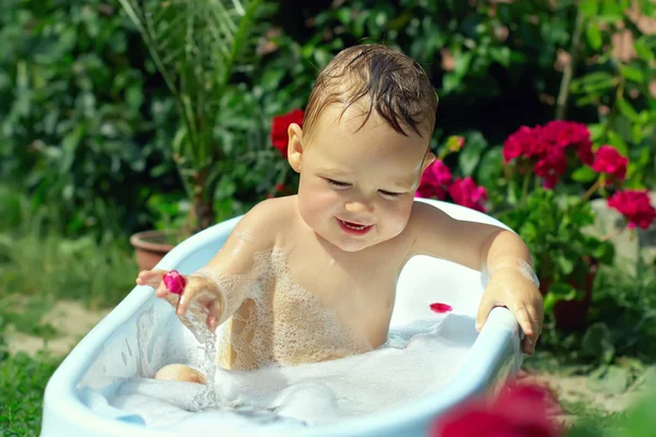 Niedlichen lustigen kleinen Jungen baden zwischen Blütenblättern im Freien auf gre — Stockfoto