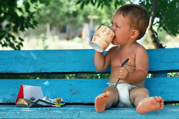 Morning ritual, small boy sitting on blue rural bench drinking coffee with — Stock Photo, Image