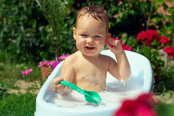 Schattige grappige kleine jongen buiten baden in groene tuin — Stockfoto