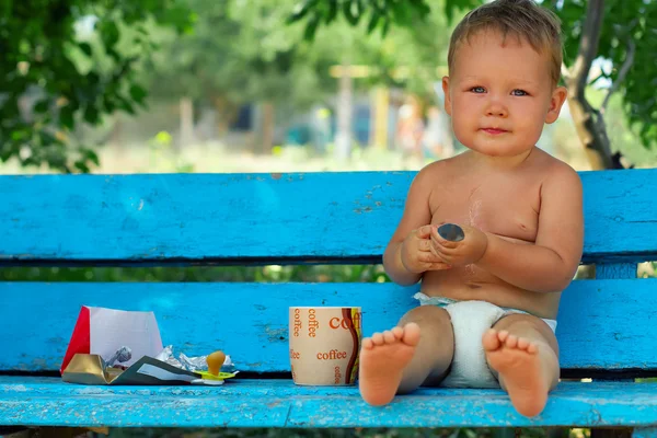 Rituel du matin, petit garçon assis sur un banc rural bleu buvant du café — Photo