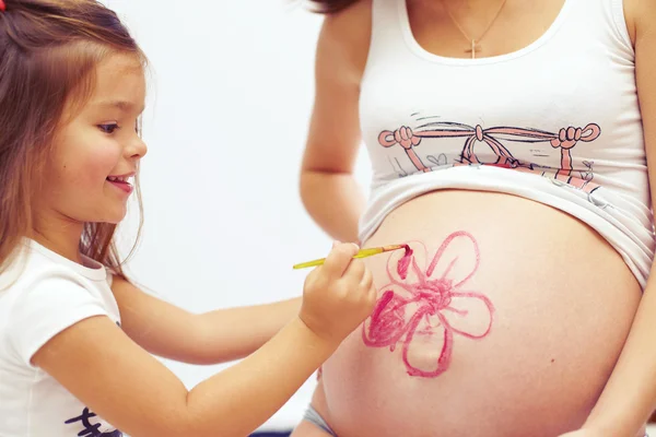 Süße Tochter bemalt Mamas schönen Bauch — Stockfoto