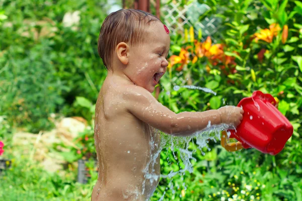 Niedlicher kleiner Junge nimmt Wasserprozeduren im Sommergarten — Stockfoto