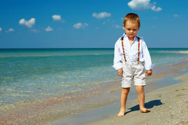 Zasněný chlapeček stojí v příboji na pláži moře — Stock fotografie