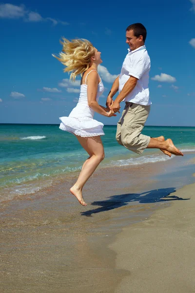 Gelukkige paar springen op het strand — Stockfoto