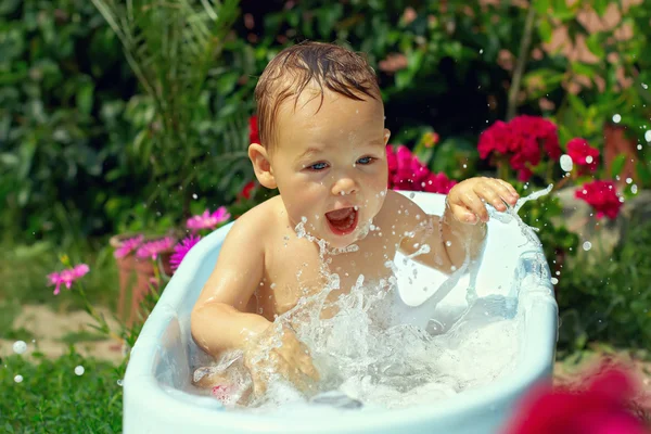 Netter lustiger kleiner Junge badet draußen im grünen Garten — Stockfoto