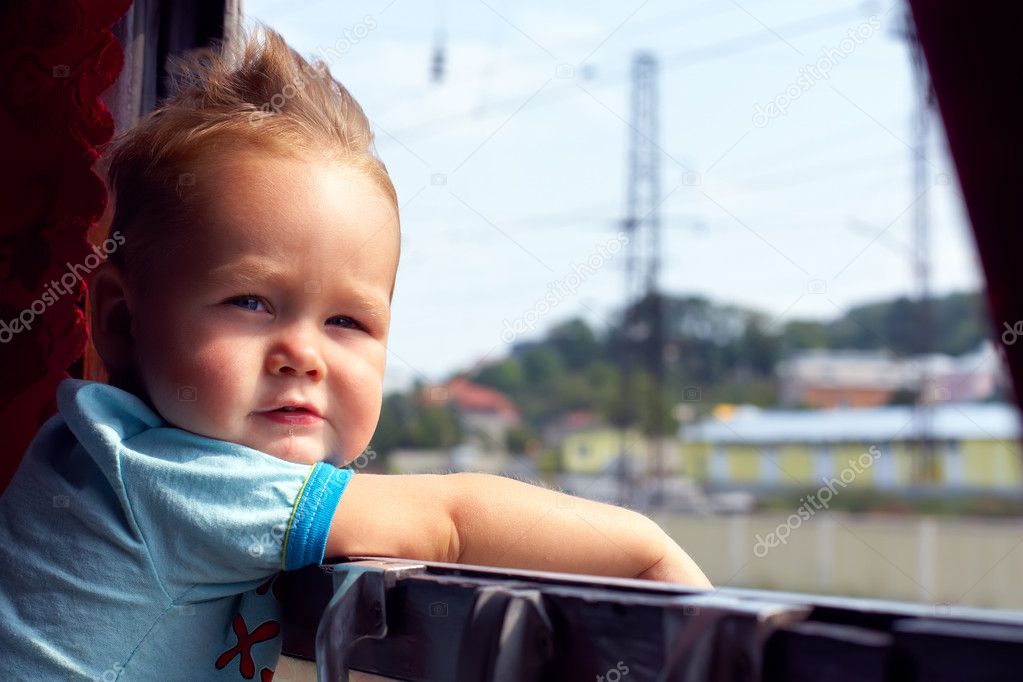 Funny little boy picking out of train window outside, while it moving. flut