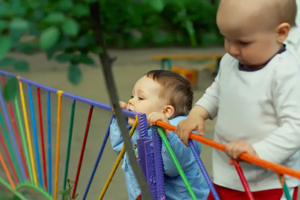 Schattige grappige kleine jongen bijten yummy kleurrijke hek buiten in kin — Stockfoto