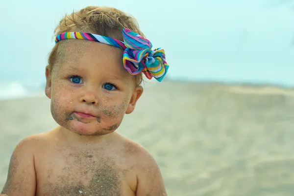 Portrait of cute funny baby smeared with sand on beach — Stock Photo, Image