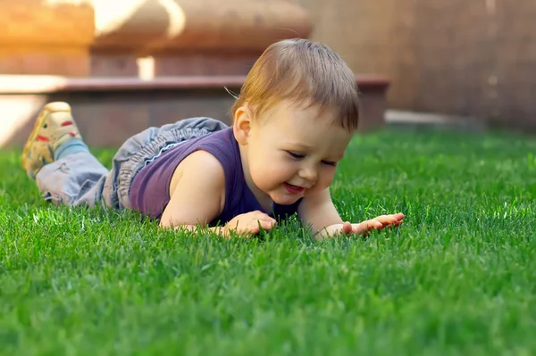 Feliz sorrindo bebê menino se divertindo mentindo e explorando gra verde — Fotografia de Stock