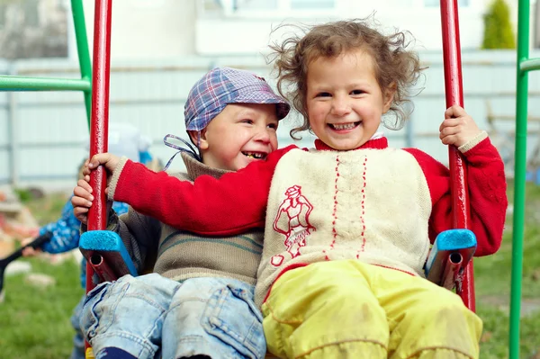 Dirty, happy little gypsy siblings on swings outdoor — Stock Photo, Image