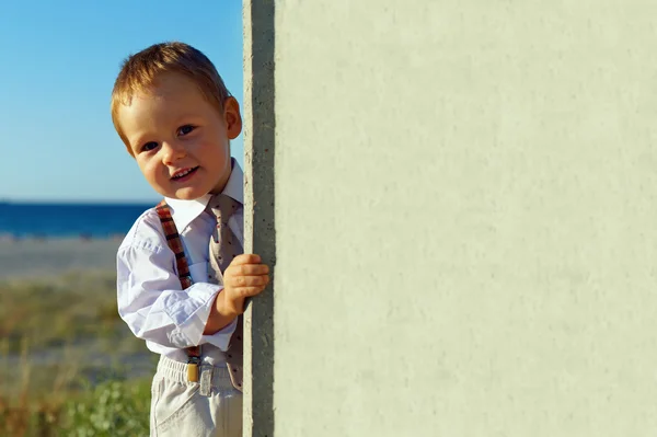 Little business baby boy holding board, sea coast background — Stock Photo, Image