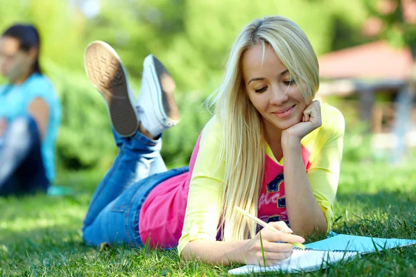 Güzel kız öğrenci dışında yeşil çimenlerin üzerine öğrenir. — Stok fotoğraf