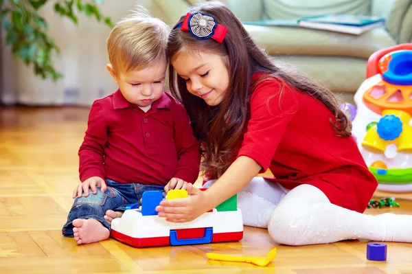 Hermosa chica jugando con su hermano pequeño en casa — Foto de Stock