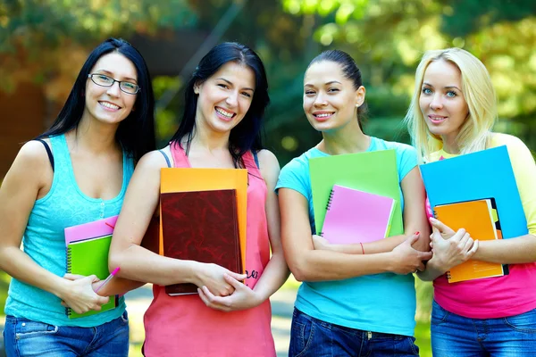 Four beautiful college students posing outside in green park — Stock Photo, Image