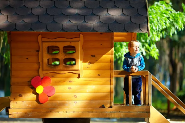 Bonito menino brincando na casa da árvore, ensolarado ao ar livre — Fotografia de Stock