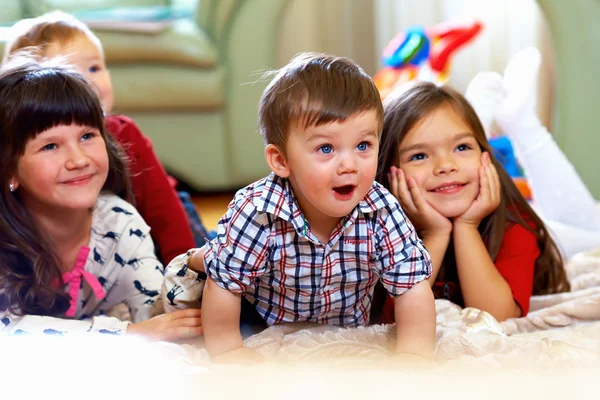 Groupe d'enfants heureux regarder la télévision à la maison — Photo