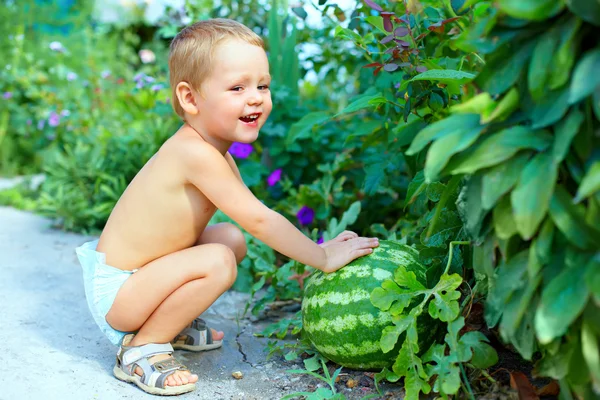 Glad pojke med stor vattenmelon i sommarträdgård — Stockfoto