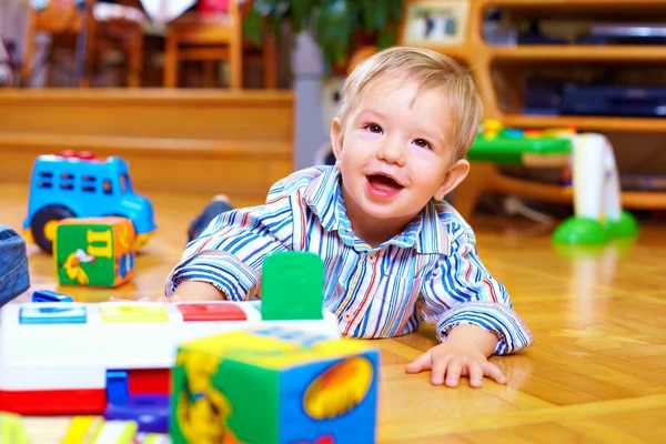 Cute baby boy playing with toys in living room Stock Picture