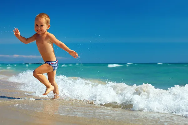 Happy baby running from surf on the beach — Stock Photo, Image