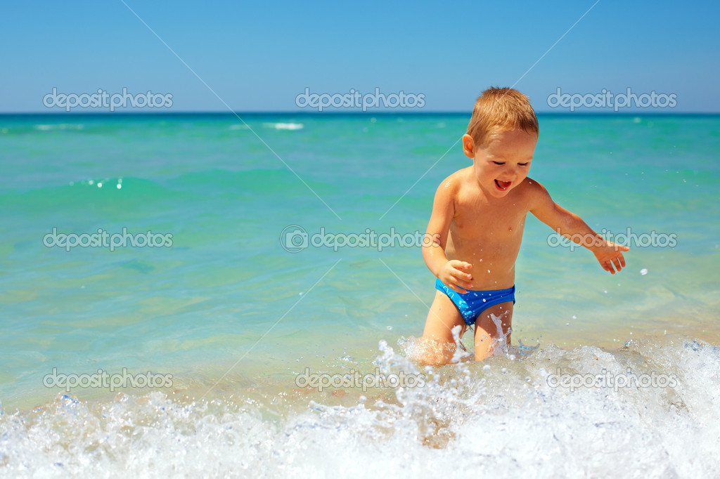 Laughing baby boy having fun in sea surf