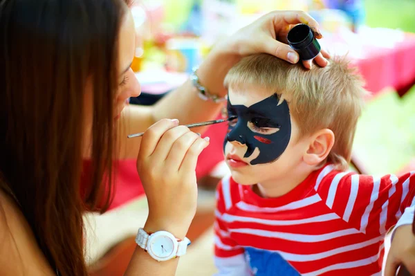 Vrouw schilderij gezicht van kind buiten — Stockfoto