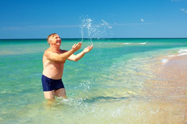 快乐的成熟男人，溅上海滩的水 — 图库照片