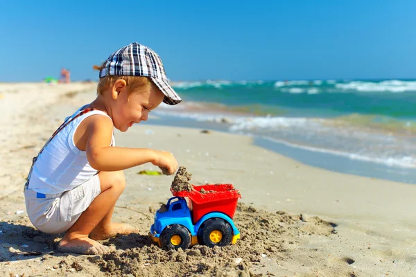 Garoto feliz bonito brincando com brinquedo na praia — Fotografia de Stock